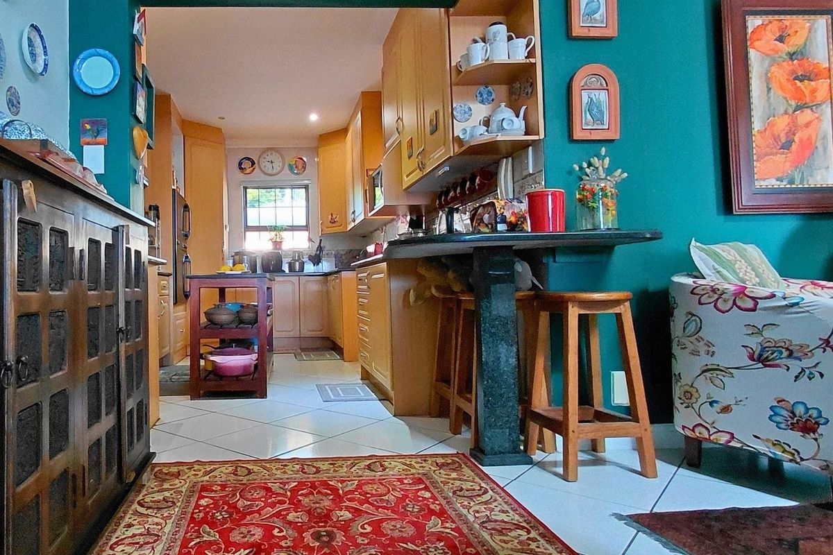 A functional kitchen featuring wooden cabinetry, a stone breakfast bar, and tiled flooring, connecting to an adjacent living area.