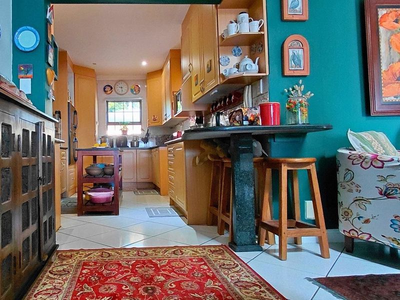 A functional kitchen featuring wooden cabinetry, a stone breakfast bar, and tiled flooring, connecting to an adjacent living area.