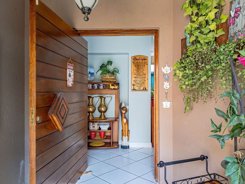 Entrance area featuring a large solid wood pivot door and ceramic tiled flooring, providing access into the home interior.