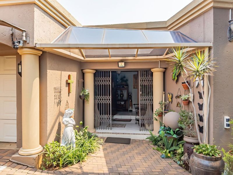 Front entrance area featuring a paved walkway, covered porch with columns, and a secure metal gate leading into the home.
