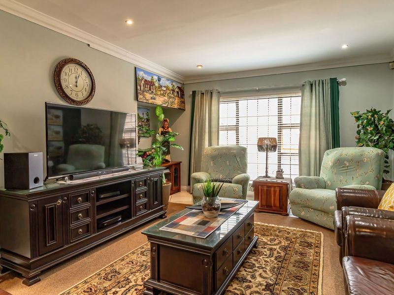 A comfortable living room featuring crown molding, recessed downlighting, and large windows with fitted blinds, creating a bright and inviting space.