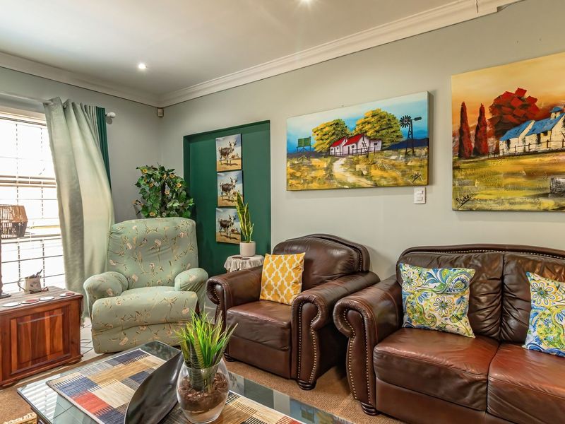 A comfortable living room featuring crown molding, recessed lighting, and large windows with blinds, creating a bright and inviting space.