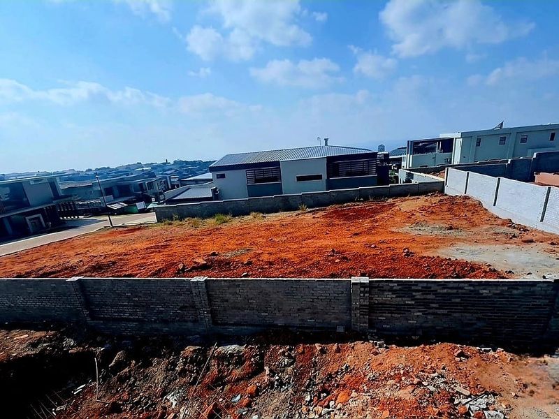 A vacant residential plot featuring a perimeter brick wall, ready for development in a established neighborhood.