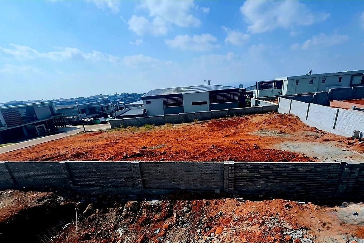 A vacant residential plot featuring a perimeter brick wall, ready for development in a established neighborhood.