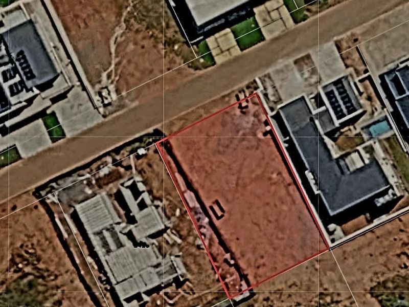 An aerial view of a vacant residential plot within a developed estate, showing the boundary lines and surrounding properties.