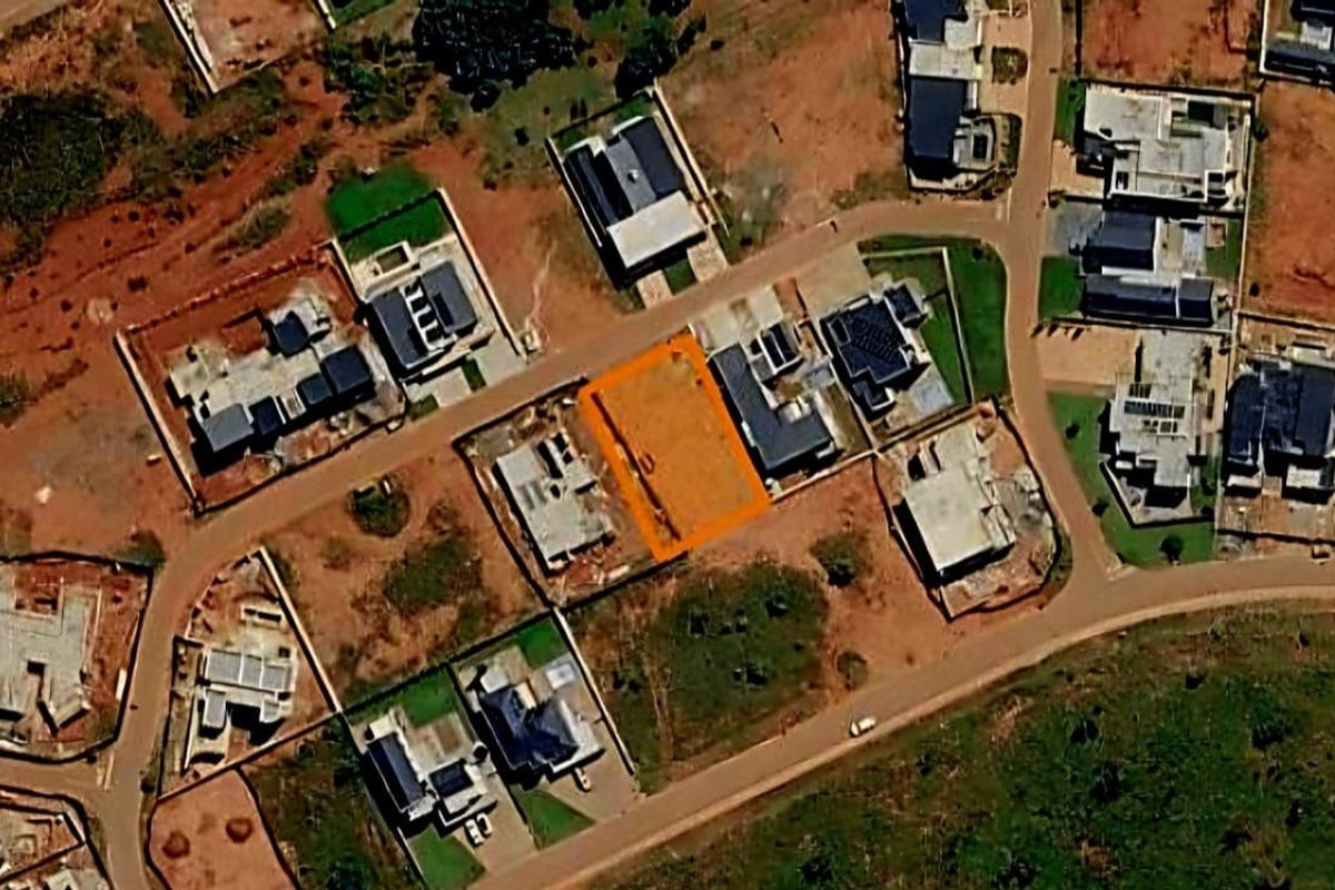 An aerial view of a vacant residential plot situated within an established housing estate, highlighting the property boundaries and surrounding neighborhood context.