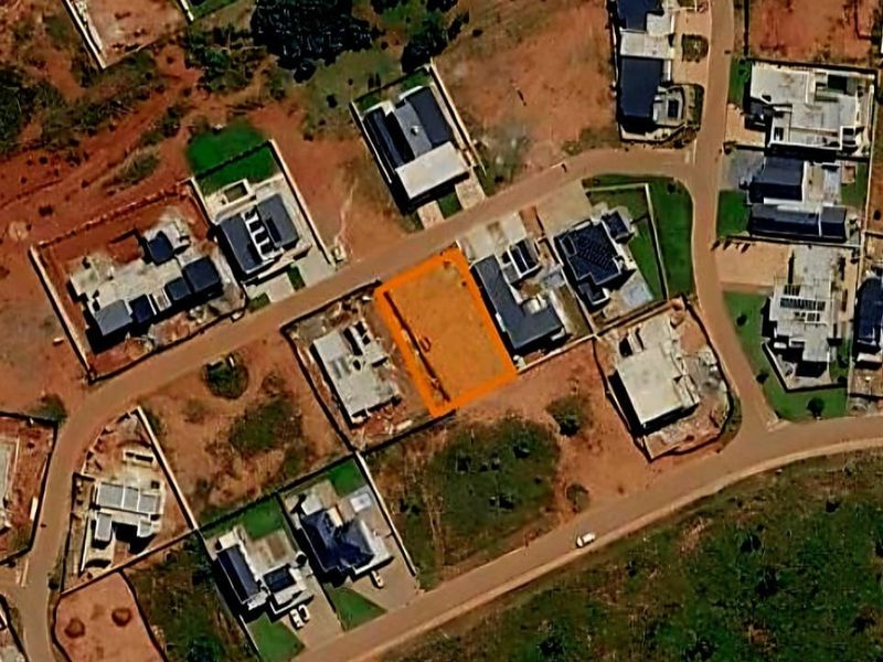 An aerial view of a vacant residential plot situated within an established housing estate, highlighting the property boundaries and surrounding neighborhood context.