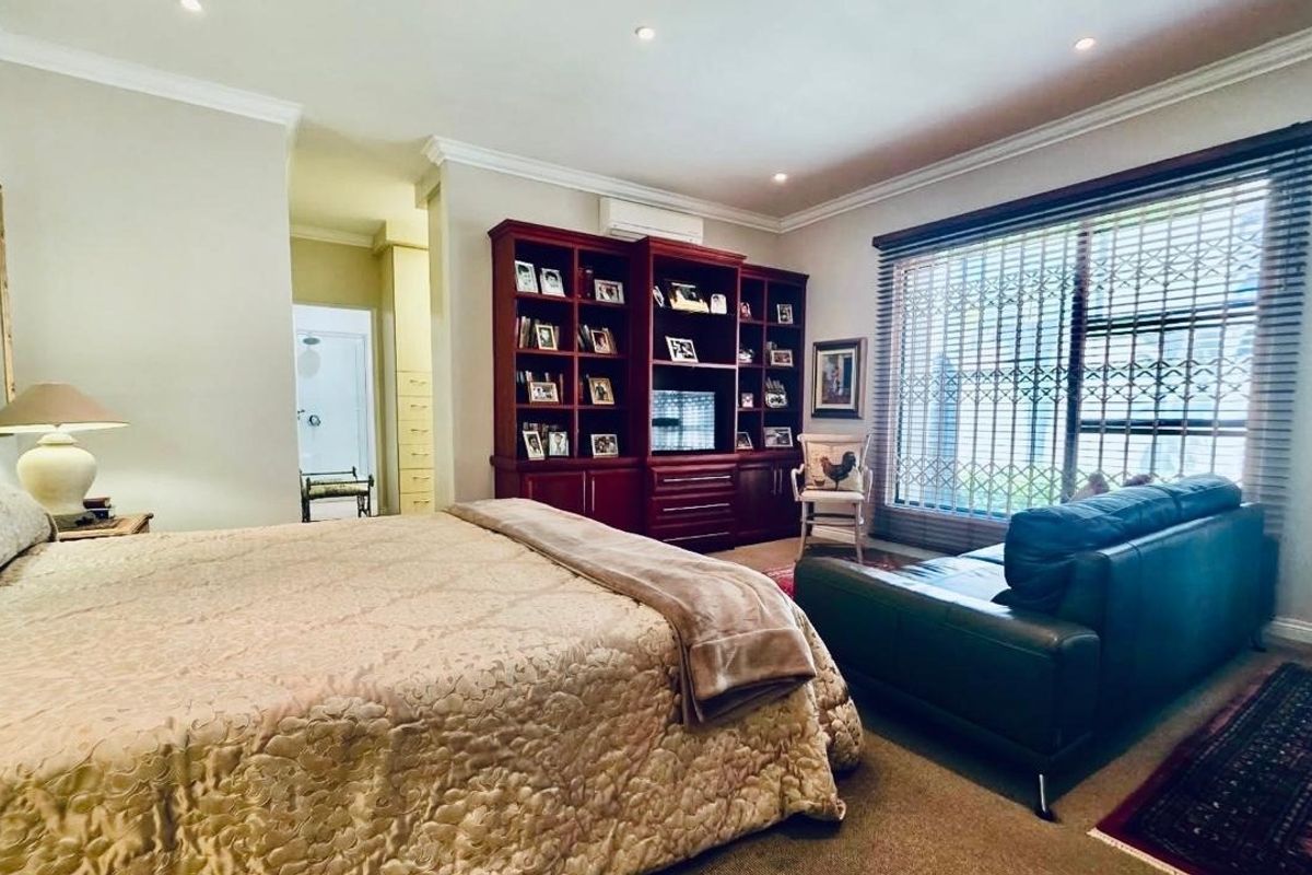 Spacious bedroom featuring built-in cabinetry, recessed downlighting, and large windows with security gates, offering a comfortable and functional living space.