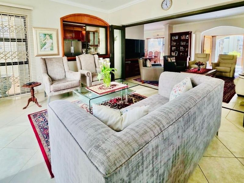Spacious open-plan living area featuring tiled flooring, bi-fold doors, and an archway connecting to the kitchen and adjacent living spaces.