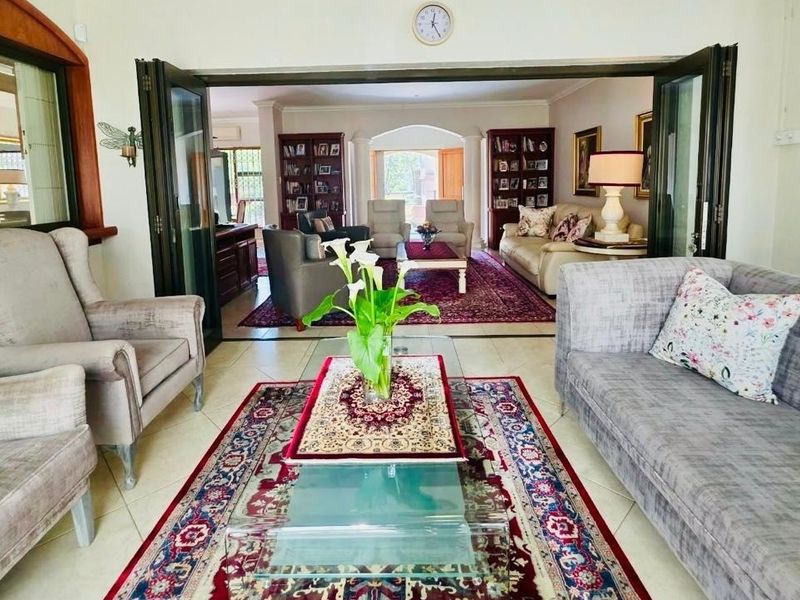Spacious living area featuring tiled flooring and large bi-fold doors that connect to an adjacent lounge space, creating an open and airy atmosphere.