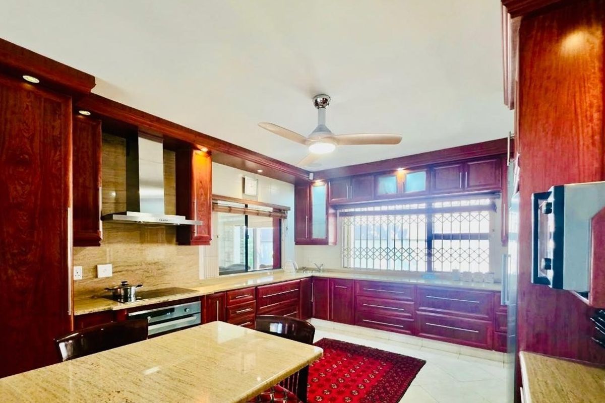 Spacious kitchen featuring extensive dark wood cabinetry, granite countertops, integrated appliances, and a ceiling fan, offering a classic and functional culinary workspace.