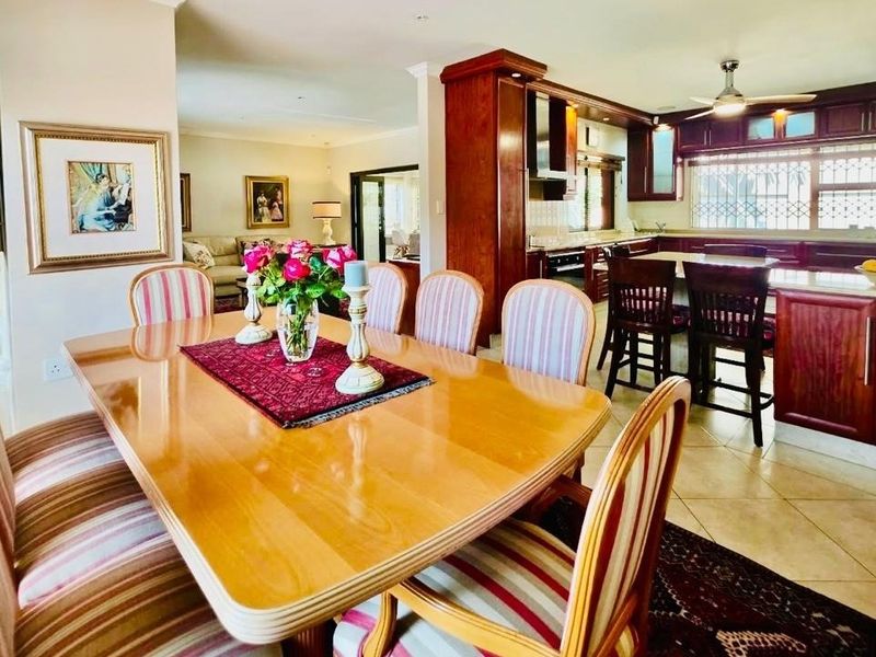 An open-plan dining and kitchen area featuring dark wood cabinetry, a central kitchen island, and tiled flooring, creating a functional and connected living space.