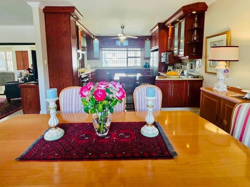 Open plan dining and kitchen area featuring dark wood cabinetry, integrated appliances, and a ceiling fan, creating a functional living space.