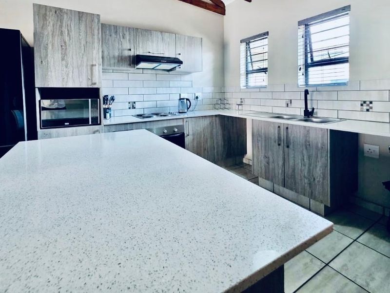 Modern kitchen featuring light wood-grain cabinetry, quartz countertops, subway tile backsplash, and integrated appliances, offering a clean and functional workspace.