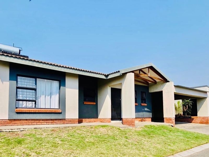Front elevation of a modern townhouse featuring a brick base, covered entrance, carport, and solar water heating system.