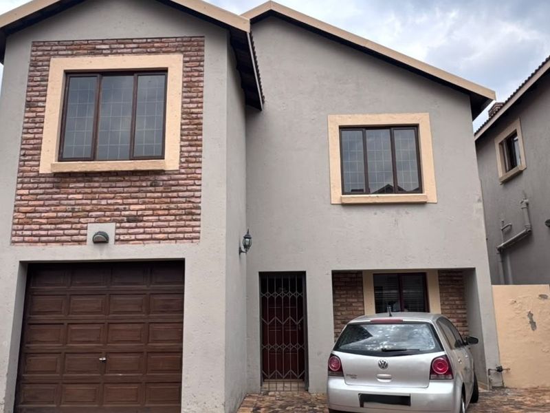 Front elevation of a double-story townhouse featuring a brick and plaster facade, integrated garage, and secure entrance.
