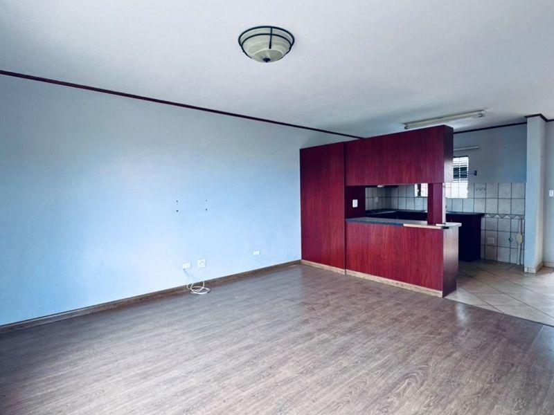 Open-plan living area featuring laminate flooring, a breakfast counter, and a semi-enclosed kitchen space with built-in cabinetry.