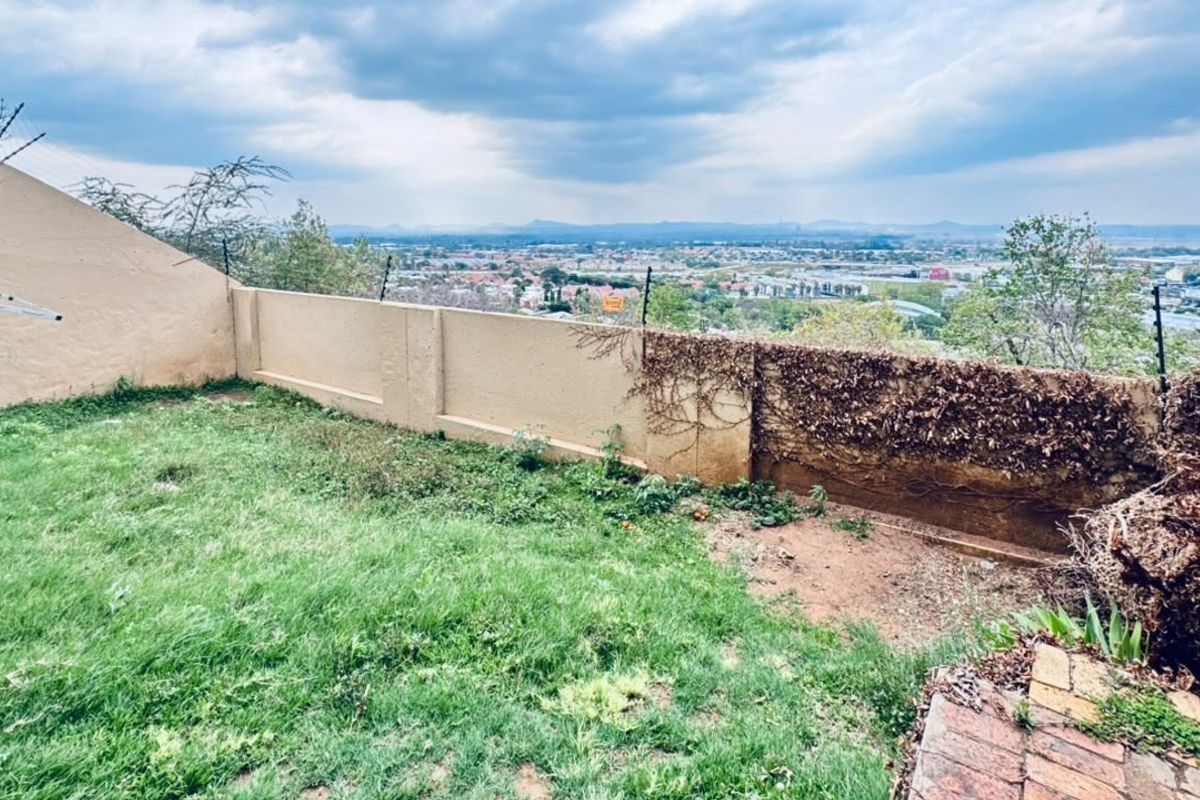 Rear garden area featuring a perimeter wall with electric fencing and expansive elevated views over the surrounding neighborhood.