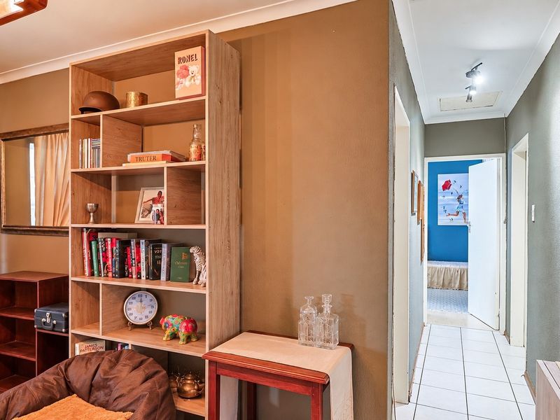 A functional hallway featuring tiled flooring and a ceiling access hatch, providing transition between the living area and adjacent rooms.