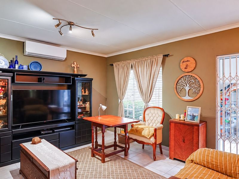 A living room featuring tiled flooring, a wall-mounted split-system air conditioner, and a security gate leading to an outdoor area.