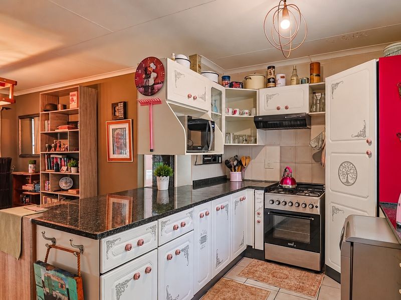 Open-plan kitchen featuring granite countertops, built-in cabinetry, and a gas stove, seamlessly flowing into the adjacent living area with tiled flooring throughout.