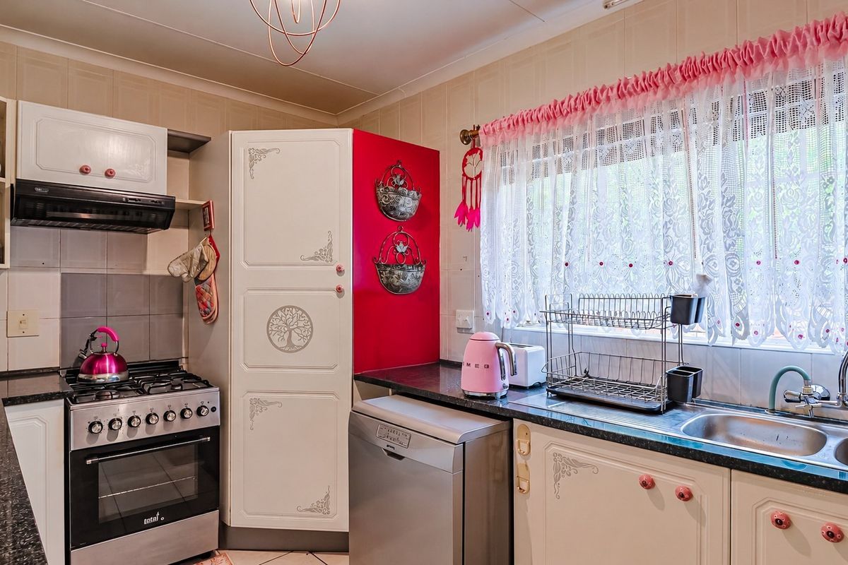 A functional kitchen featuring granite countertops, a gas stove with extractor fan, and a double basin sink with tiled splashback.