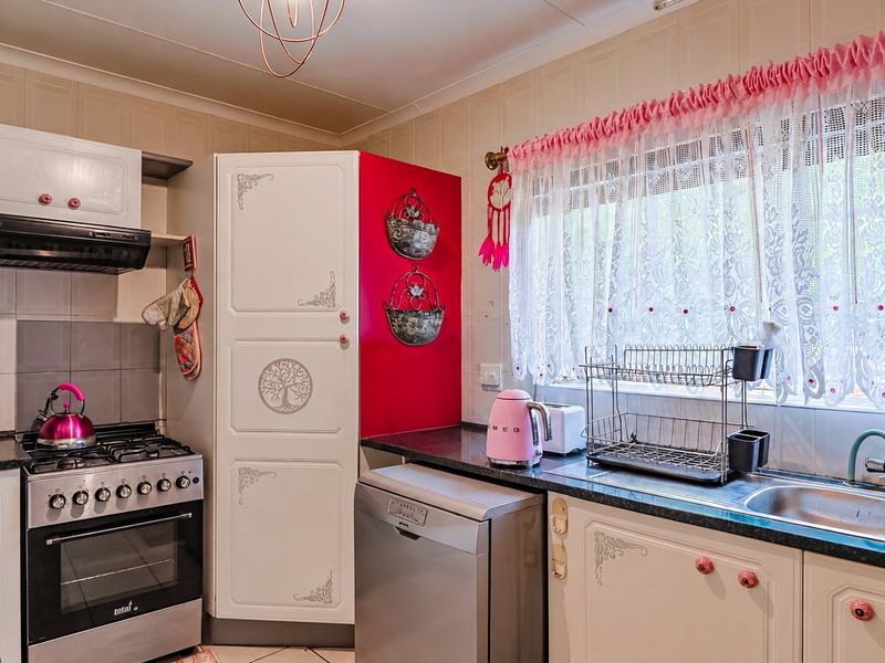 A functional kitchen featuring granite countertops, a gas stove with extractor fan, and a double basin sink with tiled splashback.