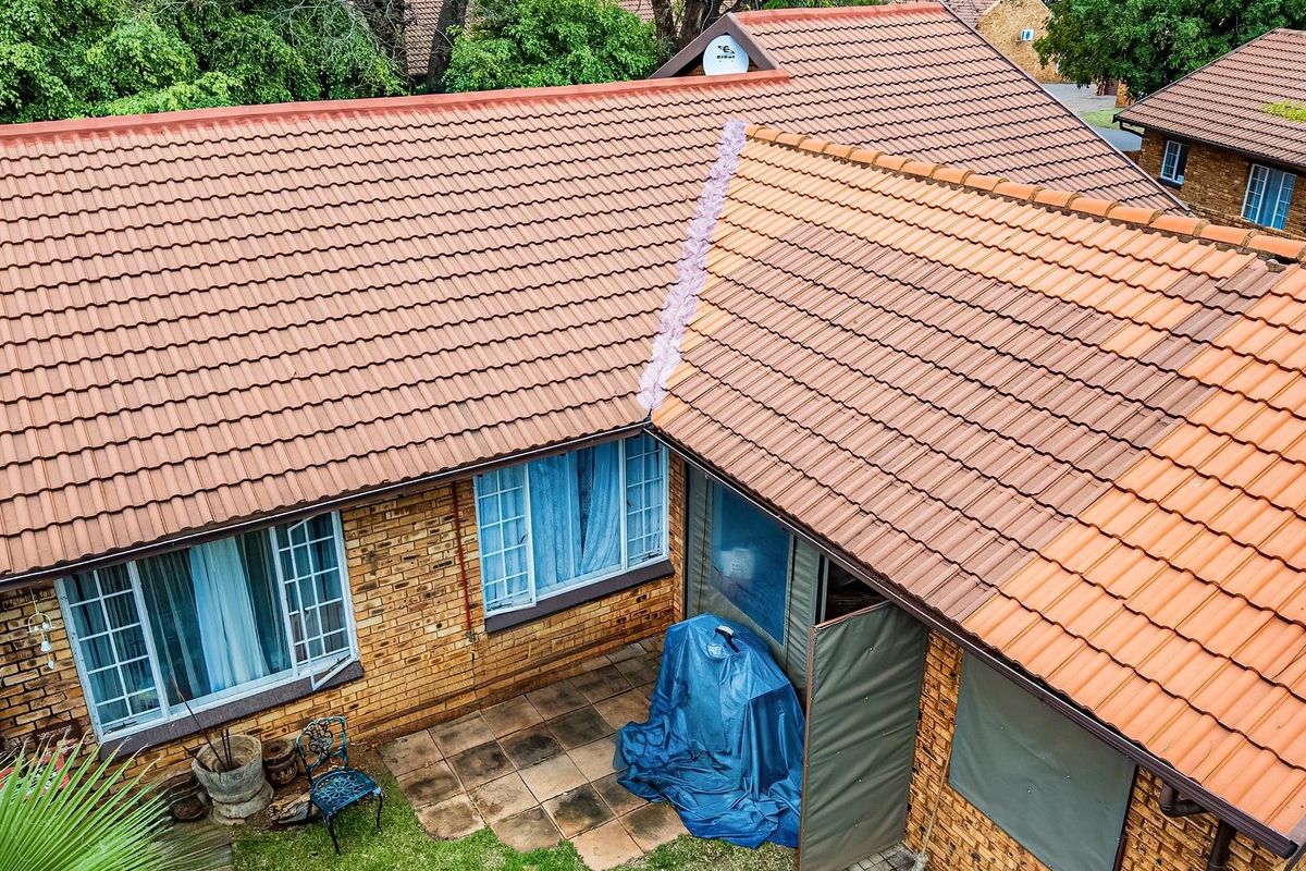 Aerial view of the townhouse exterior showing the tiled roof structure, brick facade, and a small paved patio area.