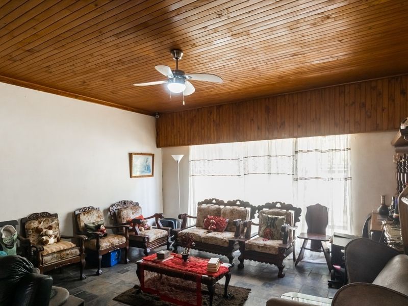 Spacious living room featuring a traditional timber tongue and groove ceiling, ceiling fan, and durable slate tile flooring.