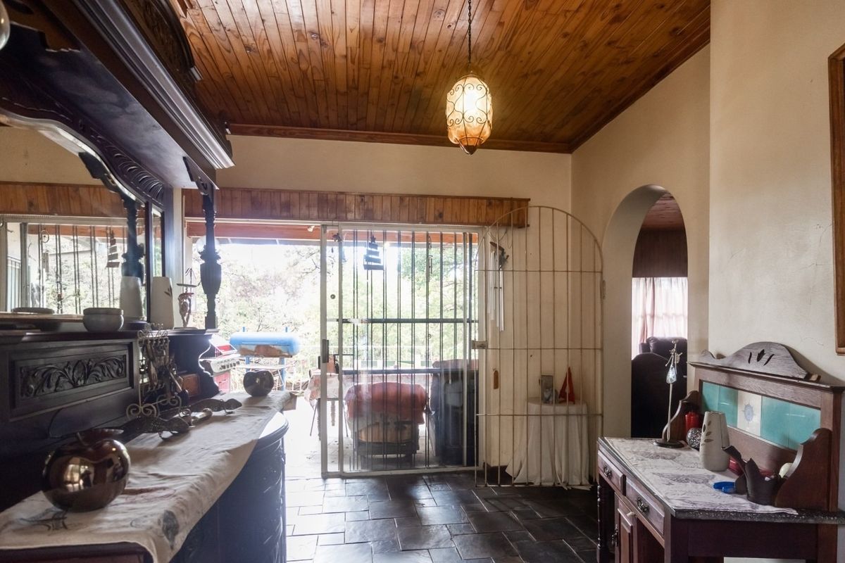 Living area featuring slate tile flooring, a timber tongue and groove ceiling, and an arched entryway leading to adjacent spaces.