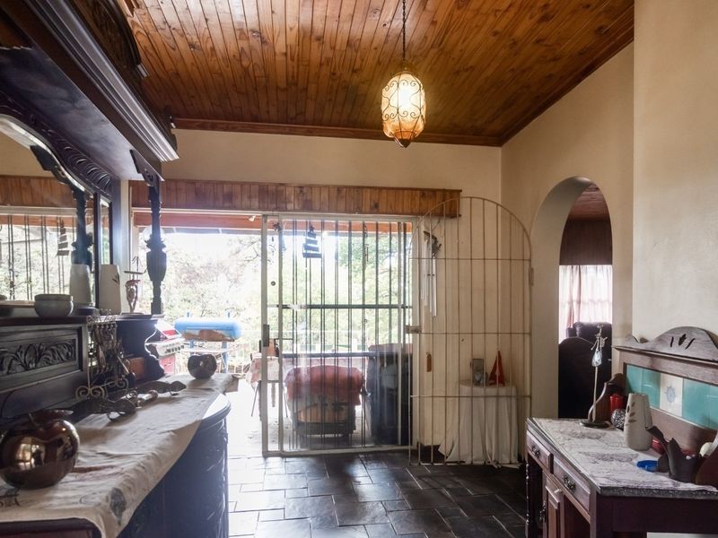 Living area featuring slate tile flooring, a timber tongue and groove ceiling, and an arched entryway leading to adjacent spaces.