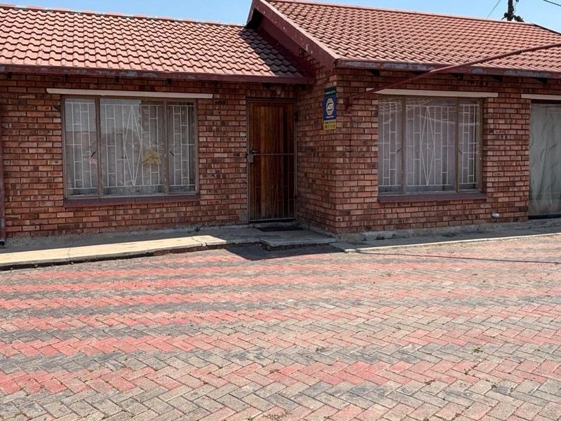 Front elevation of a face-brick house featuring a tiled roof, paved driveway, and security-fitted windows and doors.