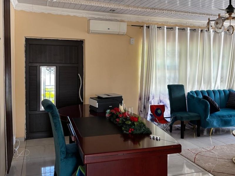 A living room featuring tiled flooring, decorative ceiling molding, a ceiling fan, and a split-system air conditioner.