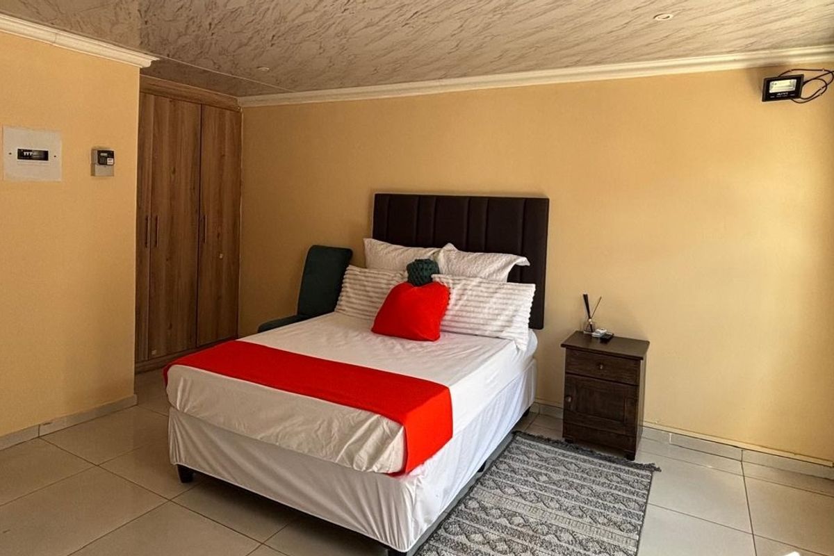 A functional bedroom featuring tiled flooring, built-in cupboards, and a security gate on the window.