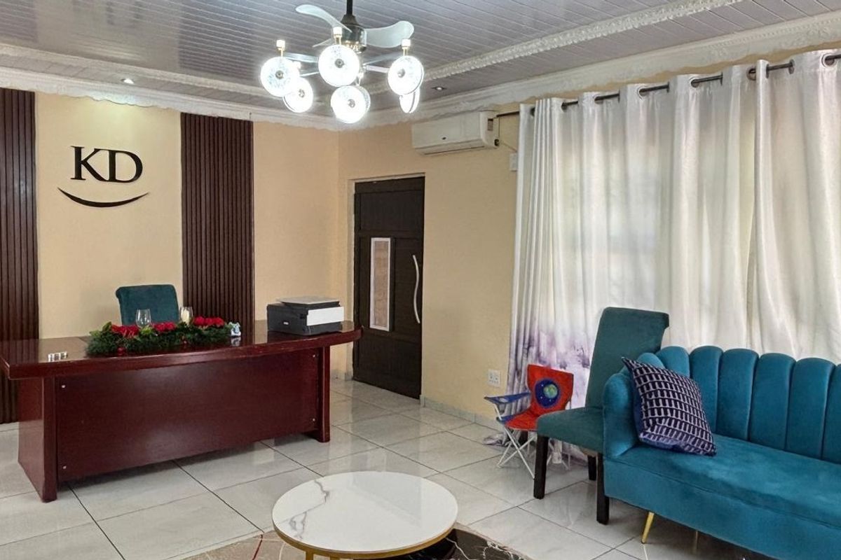 A well-maintained living area featuring tiled floors, decorative ceiling molding, modern lighting, and stylish wood wall paneling with an integrated air conditioning unit.
