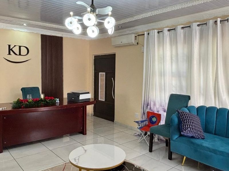 A well-maintained living area featuring tiled floors, decorative ceiling molding, modern lighting, and stylish wood wall paneling with an integrated air conditioning unit.