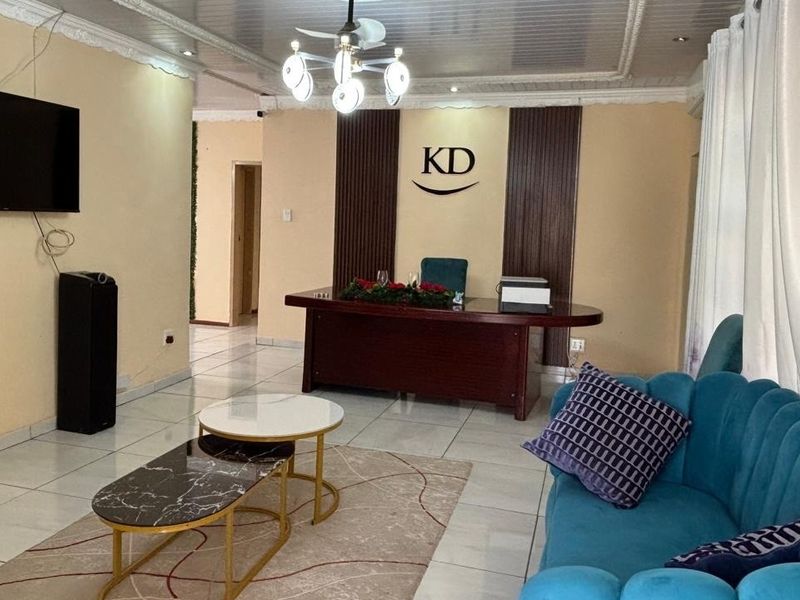 A living area featuring tiled flooring, decorative ceiling molding, and wall paneling, currently utilized as a professional office space.