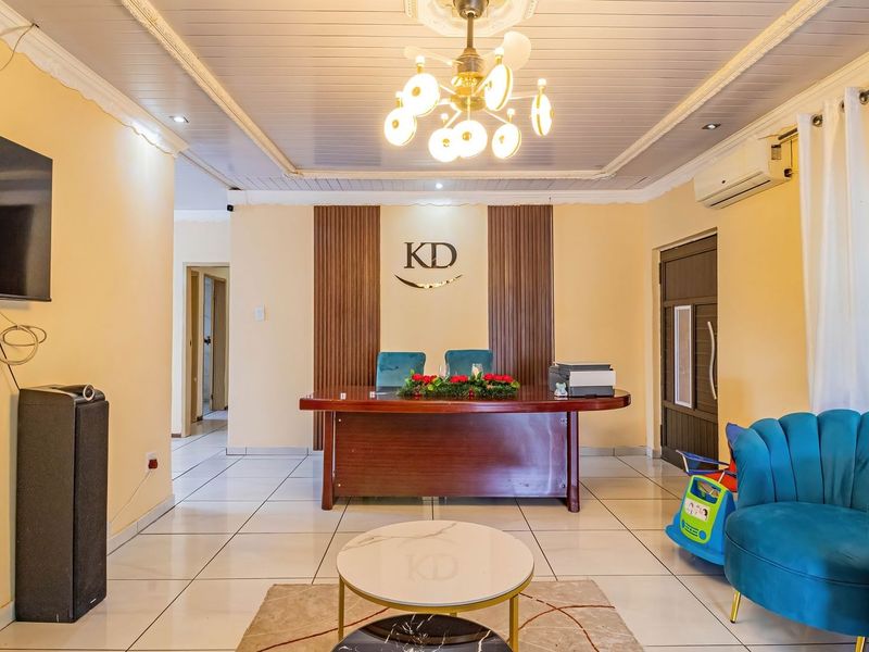 A well-maintained living area featuring tiled flooring, decorative ceiling molding, recessed lighting, and timber wall paneling, creating a professional and inviting atmosphere.