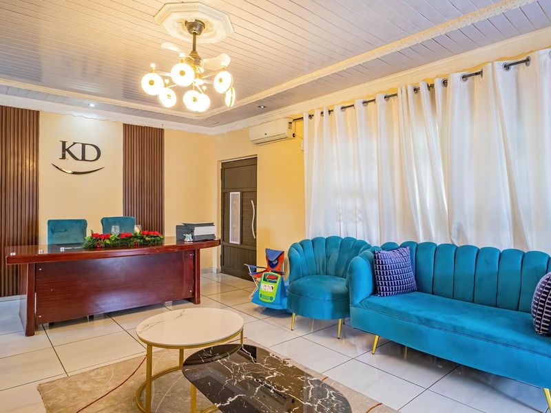 A well-maintained living area featuring tiled flooring, decorative ceiling detailing, and timber-look wall paneling, currently utilized as a professional office space.