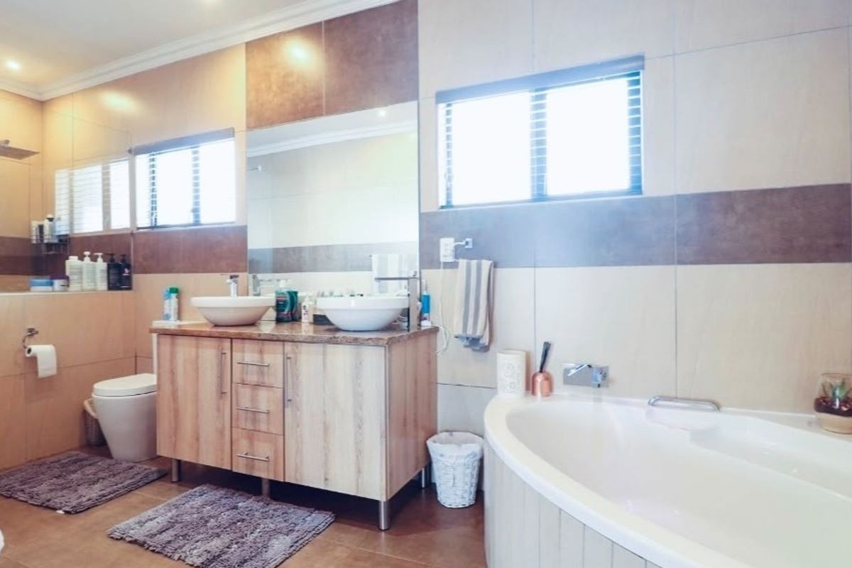 Modern bathroom featuring a double vanity with vessel sinks, a built-in bathtub, a walk-in shower, and neutral-toned wall tiling.