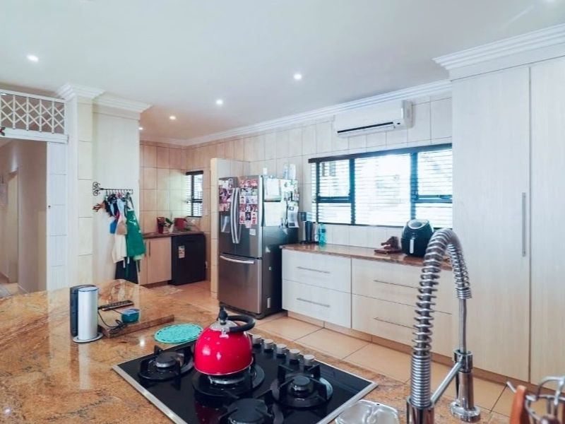 Spacious kitchen featuring granite countertops, ample built-in cabinetry, a gas hob, and a split-system air conditioner for climate control.