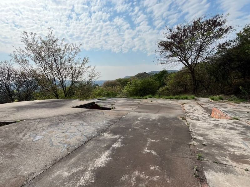 An elevated concrete platform or slab area featuring natural surroundings and views, showing signs of weathering and surface damage.