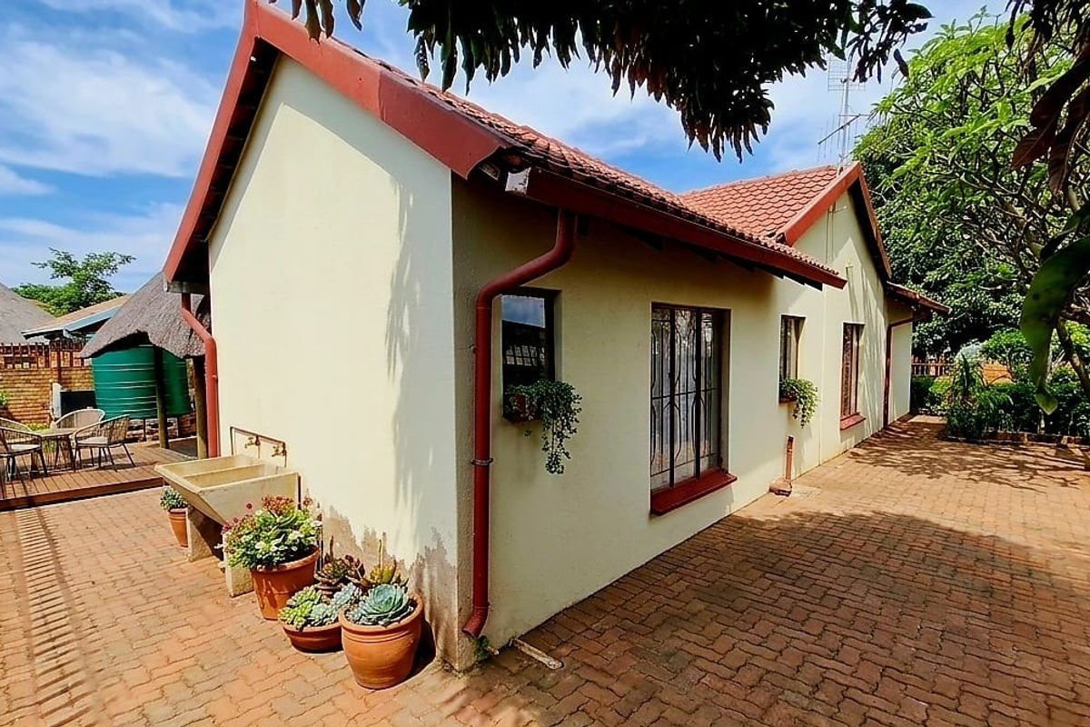 Rear exterior view of the house featuring brick paving, a tiled roof, and a functional outdoor concrete wash basin area.