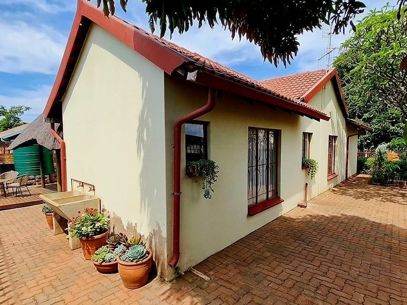 Rear exterior view of the house featuring brick paving, a tiled roof, and a functional outdoor concrete wash basin area.
