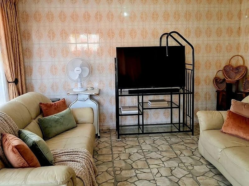 A living room featuring dated ceramic wall and floor tiles, providing a neutral base for potential modern interior updates.