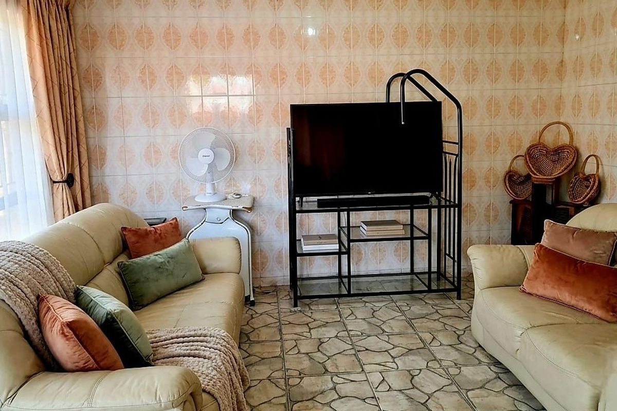 A living room featuring dated ceramic wall and floor tiles, providing a neutral base for potential modern interior updates.