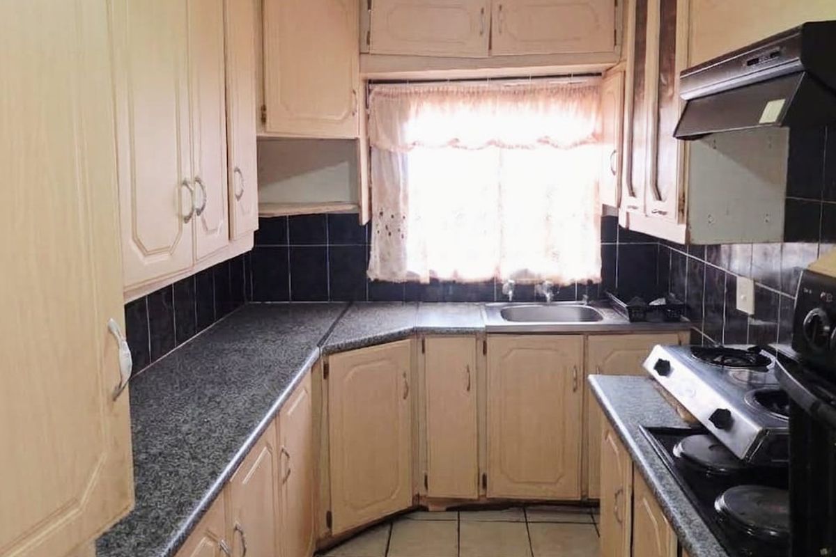 A functional kitchen featuring laminate cabinetry, granite-look countertops, a built-in oven with gas hob, and a tiled backsplash.