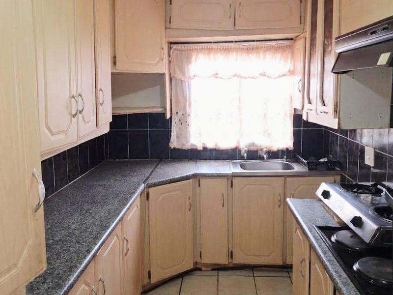 A functional kitchen featuring laminate cabinetry, granite-look countertops, a built-in oven with gas hob, and a tiled backsplash.