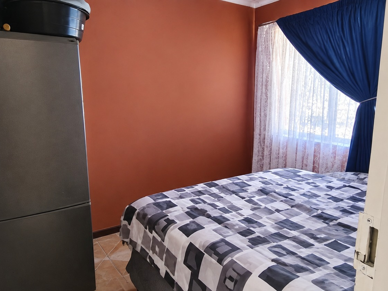 A bedroom featuring tiled flooring and a window with curtains.