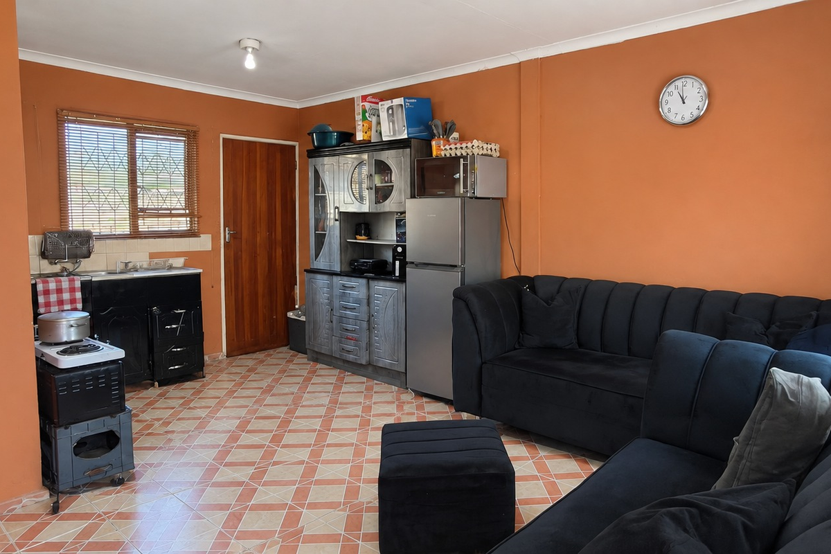 Open plan living area featuring tiled flooring, a compact kitchen corner with sink, and direct access to an exterior door.